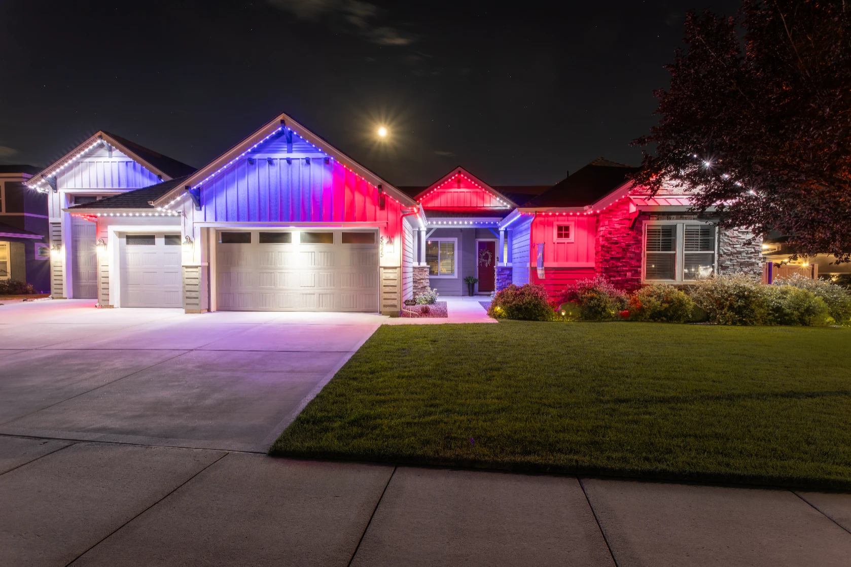 Patriotic lighting reflecting on a driveway during an evening celebration
