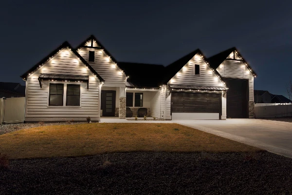 Cool white perimeter lighting outlining a wide three-car garage elevation