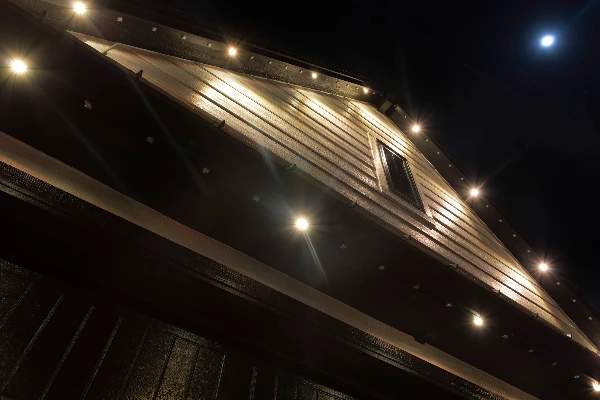 Evening accent lighting emphasizing the dormers and steep gables of a large home
