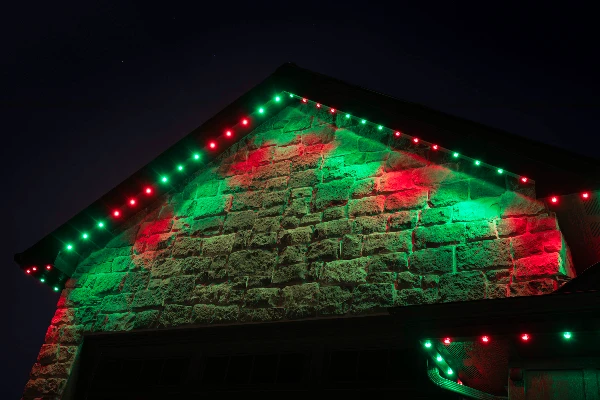 Multicolor birthday lighting animating across the front elevation of a house