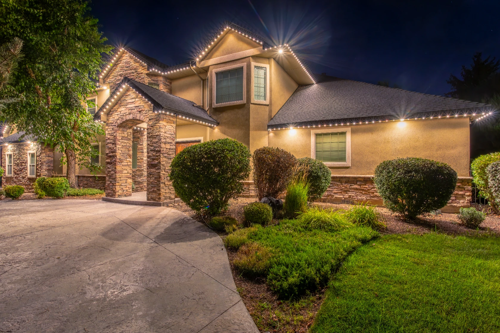 Permanent LED channel lighting highlighting the peaks of a brick two-story home