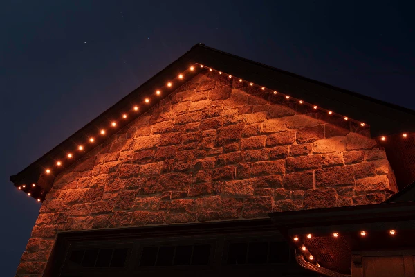 Aerial night view of a home lit in festive multicolor holiday lighting