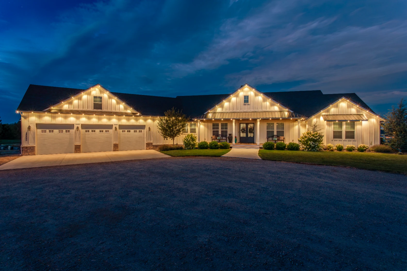 Downlit permanent lighting washing the stone facade of a craftsman-style home