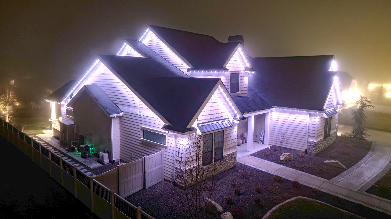 Dusk photo of a home with even white lighting across every eave and peak