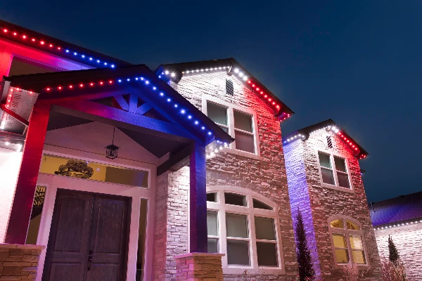 Red and green Christmas lighting alternating along the roofline of a two-story home