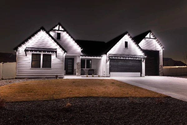 Warm accent lighting along a covered porch and columns of a ranch-style house