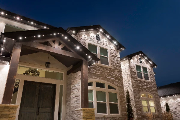 Soft white eave lighting outlining the gables of a modern farmhouse after sunset