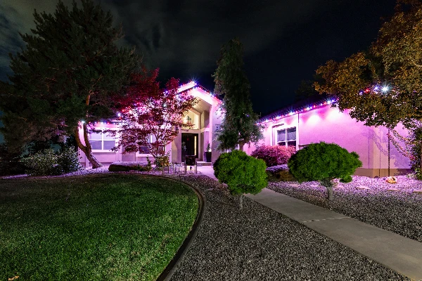 Aerial night view of a home lit in festive multicolor holiday lighting