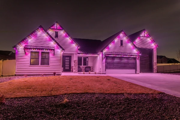 Orange and purple Halloween lighting glowing across a home's eaves and gables