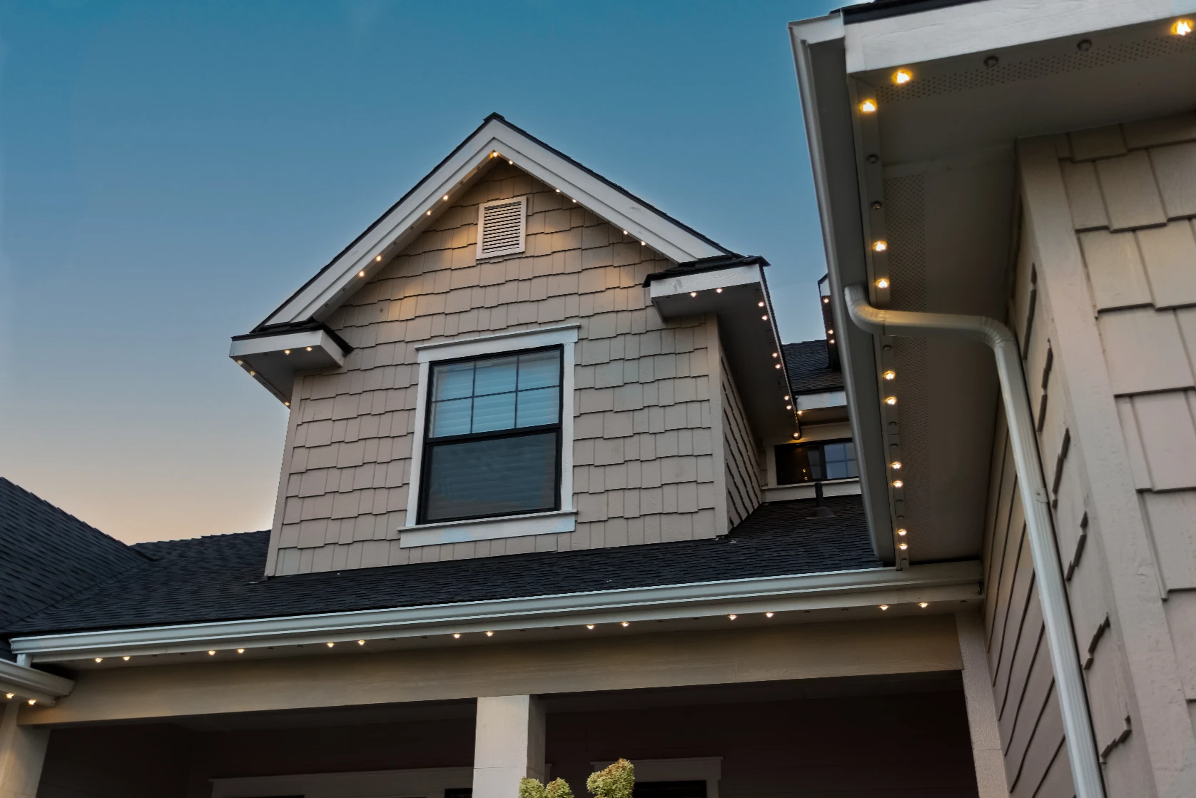 Evening accent lighting emphasizing the dormers and steep gables of a large home