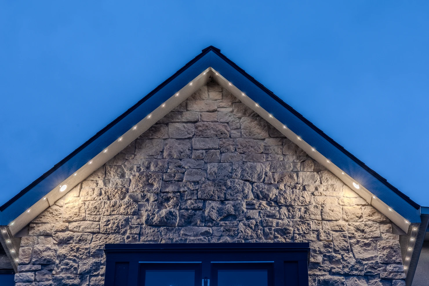 Permanent lighting outlining the full front elevation of a suburban two-story home
