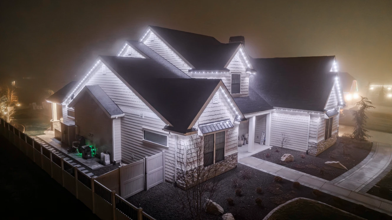 Warm white permanent accent lighting tracing the roofline of a two-story stucco home at dusk