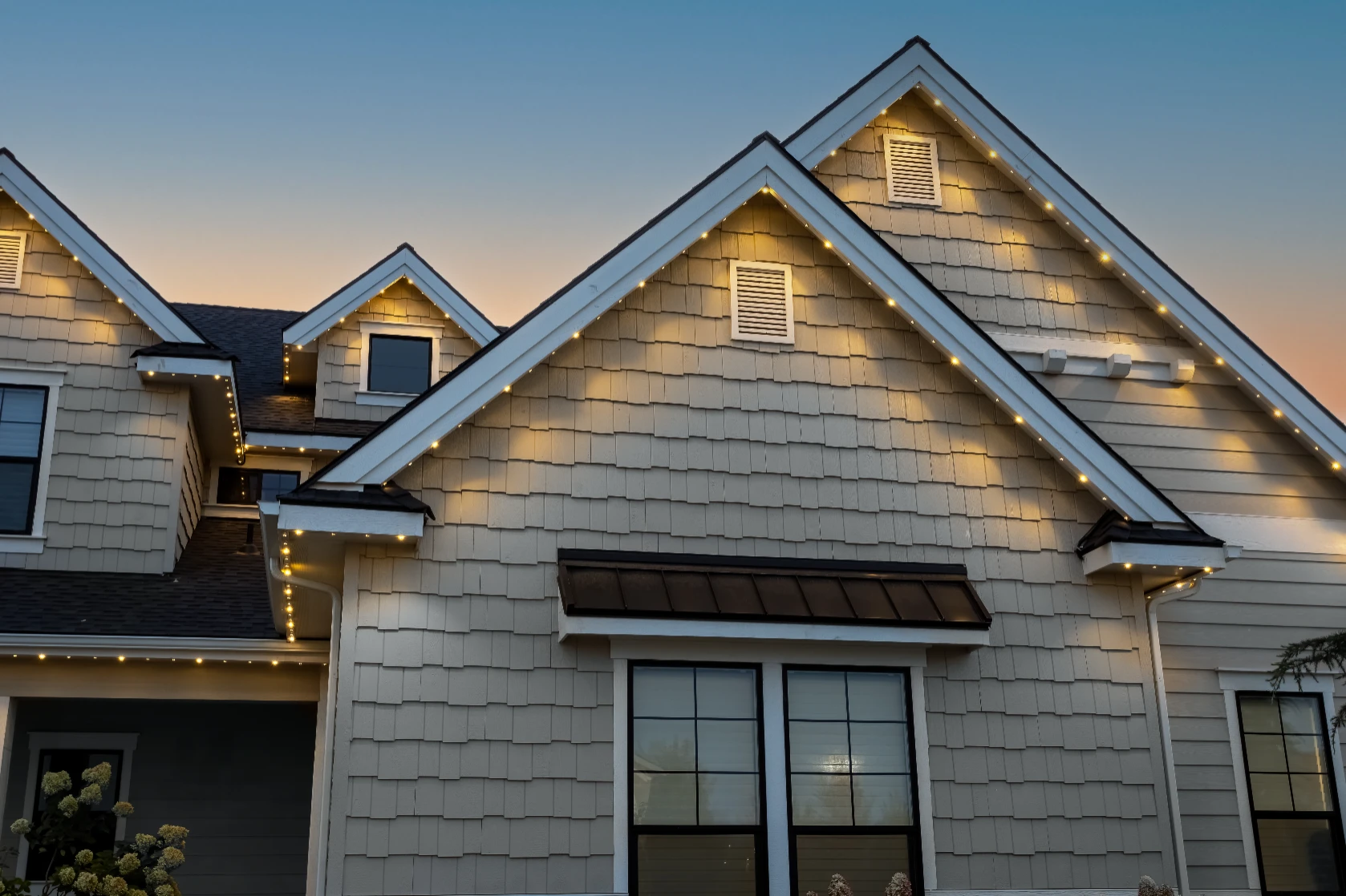 Aerial view of a home with warm white roofline lighting glowing at night
