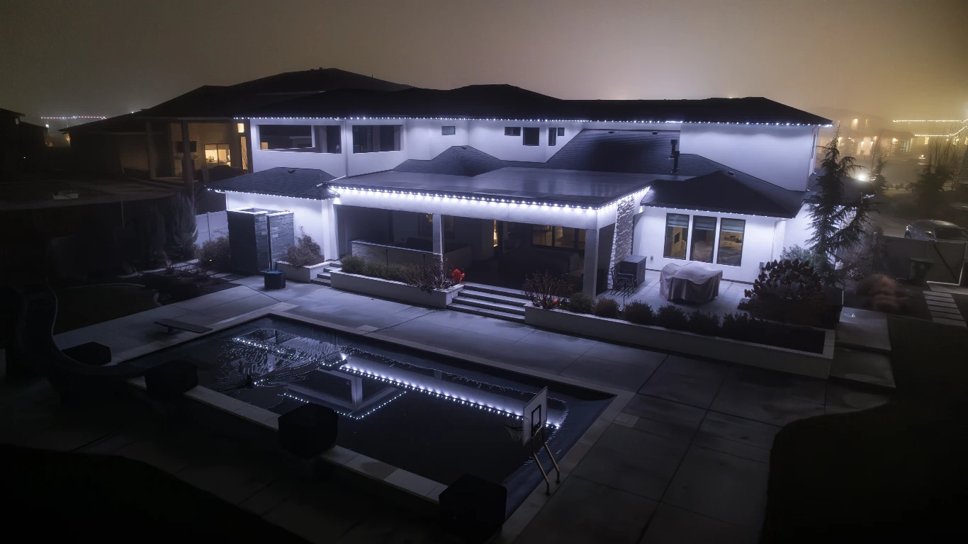 Soft white eave lighting outlining the gables of a modern farmhouse after sunset