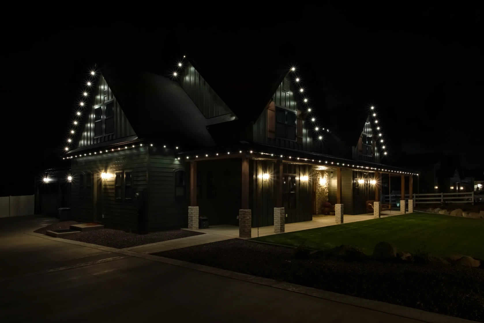 Dusk photo of a home with even white lighting across every eave and peak