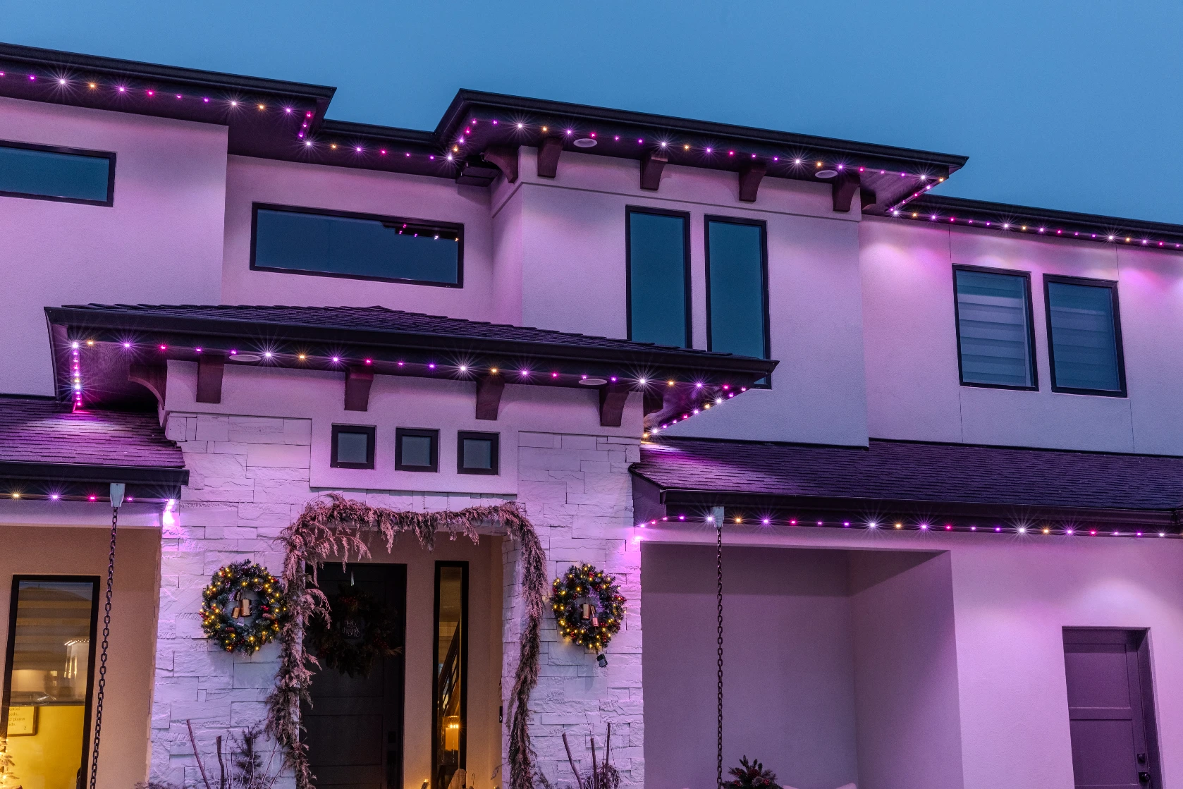 Teal and purple party lighting washing across a home's front facade