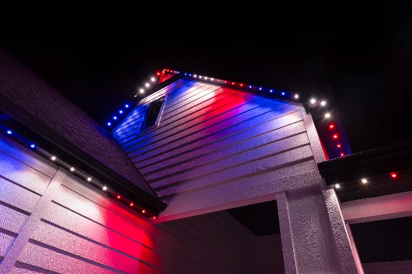 Multicolor birthday lighting animating across the front elevation of a house