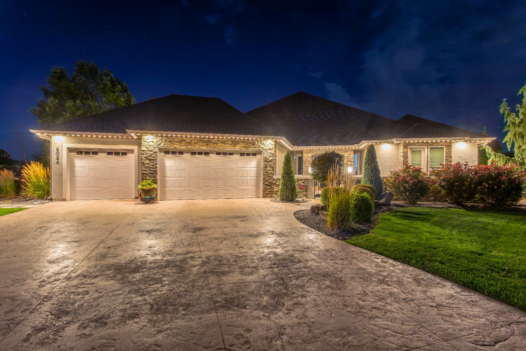 Cool white perimeter lighting outlining a wide three-car garage elevation